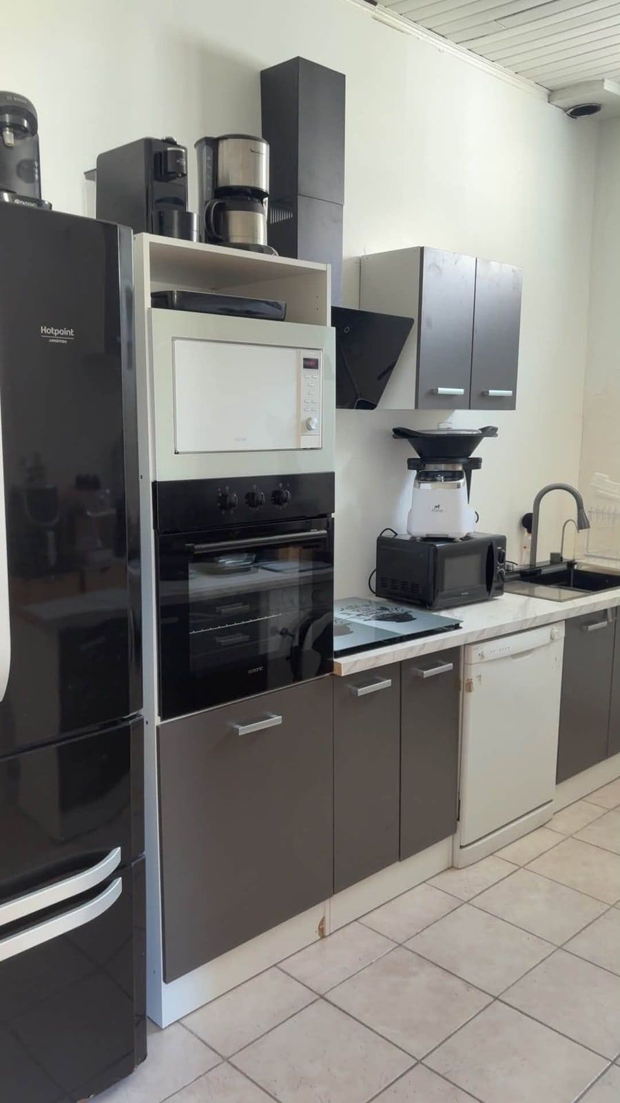La même cuisine terminée : murs peints en blanc, électroménager et meubles installés.